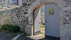 Ein Steinhaus mit einer Holztür und einem Schild, das angibt, dass es sich um ein Gîte in Frankreich handelt.