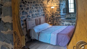 Ein rustikales Schlafzimmer mit Stehwänden, einem hölzernen Bett und einer einzelnen Nachttischlampe.