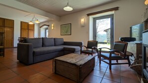 Ein geräumiges Wohnzimmer mit einer Eckcouch, einem Holztisch und einem Fernseher.