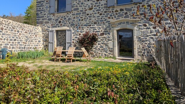 Ein Steinhaus mit Garten und Sitzbereich im Freien.