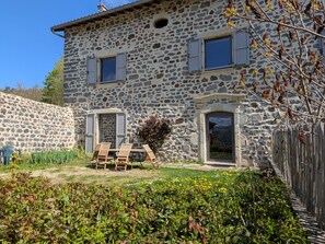 Ein Steinhaus mit Garten und Sitzbereich im Freien.