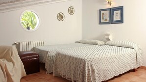 Un dormitorio con dos camas, una ventana, un radiador y detalles decorativos en la pared.