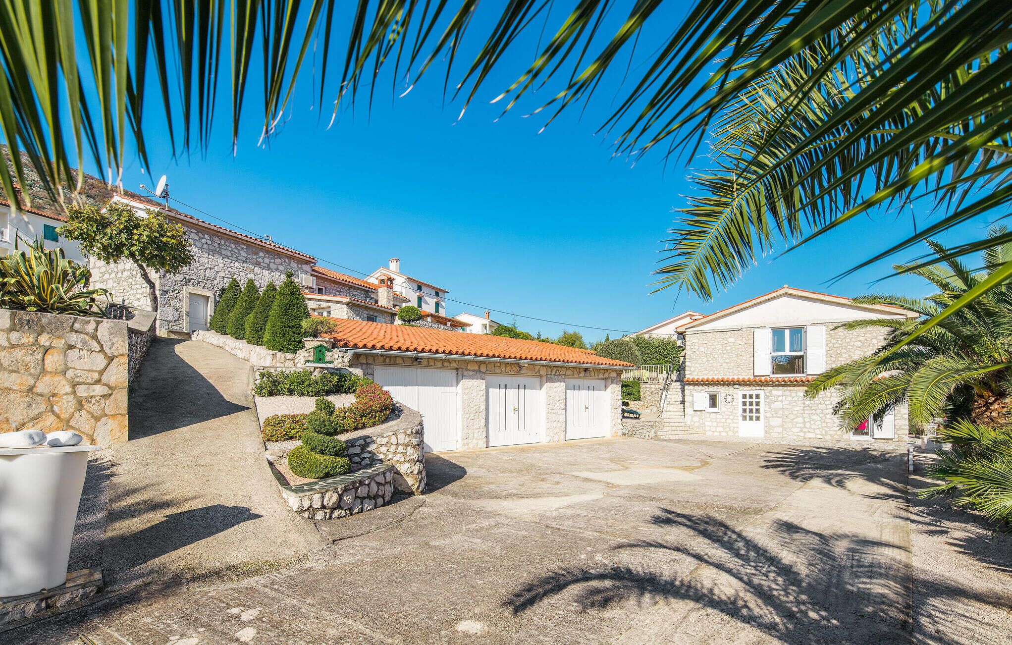 Un patio con edificios de piedra, un muro de piedra y una palmera.