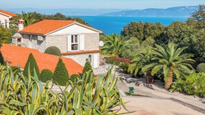 A stone house with a red-tiled roof, surrounded by lush greenery and palm trees, overlooking a coastal view. - 1 bedroom amazing apartment in Ravni (Ravni)