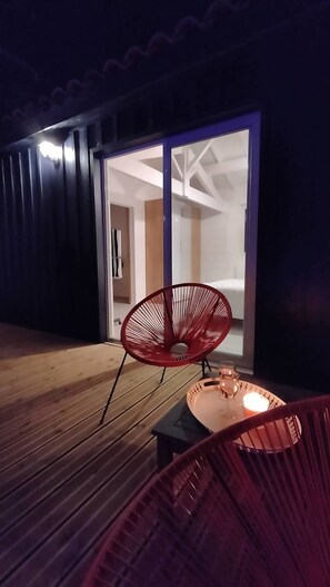 A wooden deck with a red chair and a table with a candle. - Wooden home, heated pool, AC, Villereal, 8 guests (DEVILLAC)