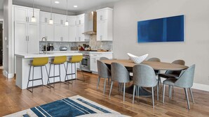 Una cocina moderna con armarios blancos, una isla central y taburetes de bar.
