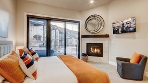 Un dormitorio con una cama grande, una chimenea, un sofá y un televisor.