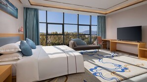 A hotel room with a bed, a desk, a TV, and a view of the mountains. - Microtel by Wyndham Lijiang (Lijiang)