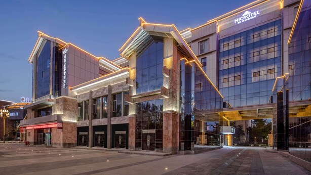 A modern hotel with a prominent entrance, large windows, and a well-lit facade. - Microtel by Wyndham Lijiang (Lijiang)