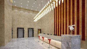 A lobby with marble flooring, a reception desk, and two elevators. - Microtel by Wyndham Lijiang (Lijiang)