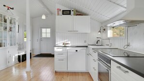 Una cocina moderna con muebles blancos, lavavajillas, horno y microondas sobre la encimera.