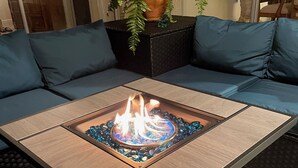 A modern living room with a sectional sofa, a glass-top coffee table with a fire feature, and a potted plant. - Holidays in Paradise! NO bridges, NO locks to the Gulf of Mexico! (Cape Coral)
