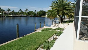 A waterfront property with a dock, palm trees, and a pathway leading to a building. - Holidays in Paradise! NO bridges, NO locks to the Gulf of Mexico! (Cape Coral)