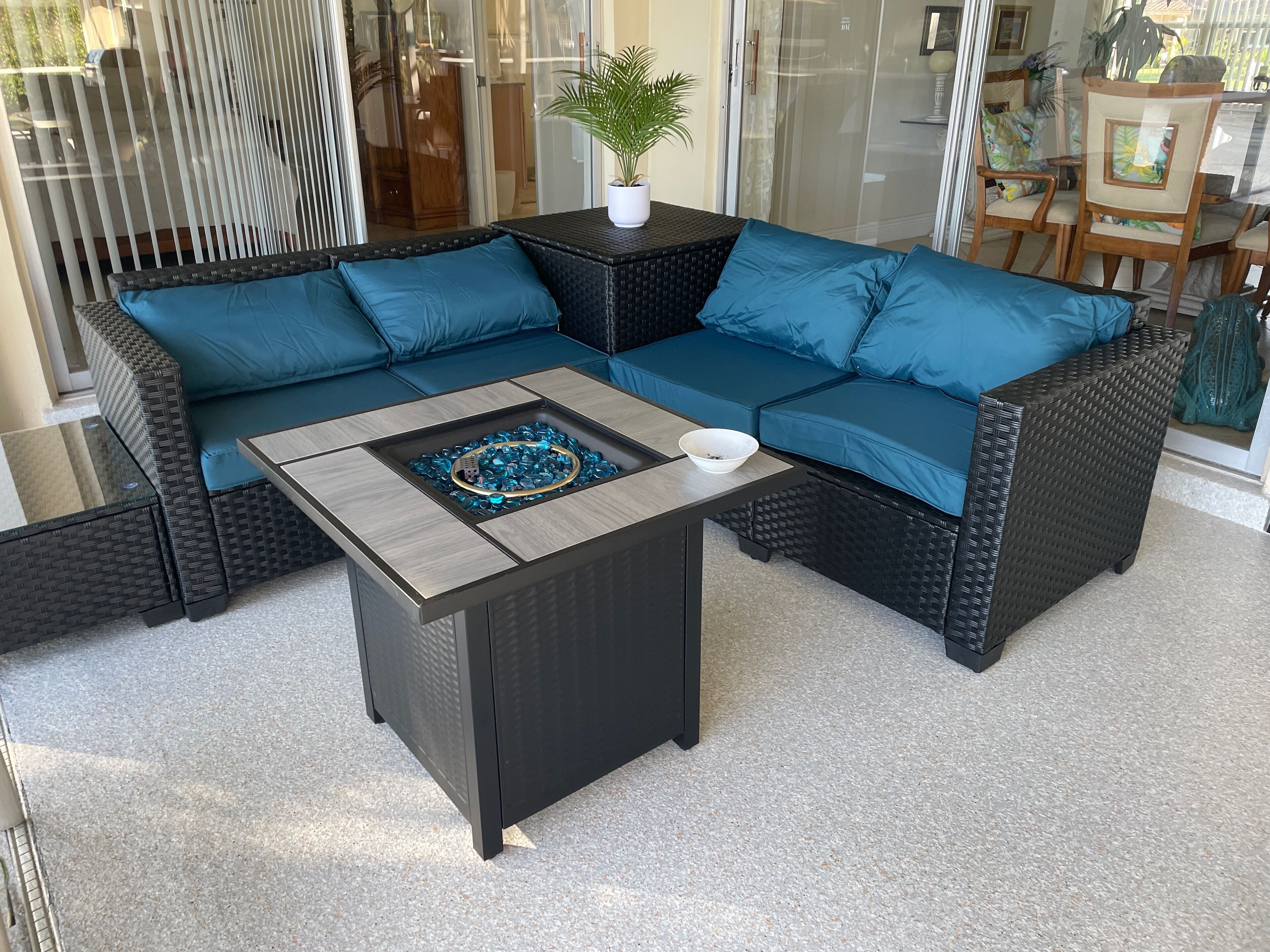 A sectional sofa with blue cushions and a small table with a decorative bowl and a plant.