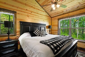 Une chambre dans une cabane en bois, avec un lit, des tables de chevet et une fenêtre donnant sur la forêt.