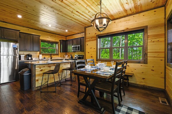 L’intérieur d’un chalet en bois comprend une cuisine, un coin repas et de grandes fenêtres.