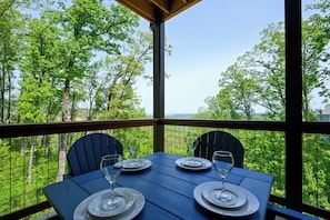 Une table dressée pour quatre personnes, avec une vue pittoresque sur les arbres et les collines.