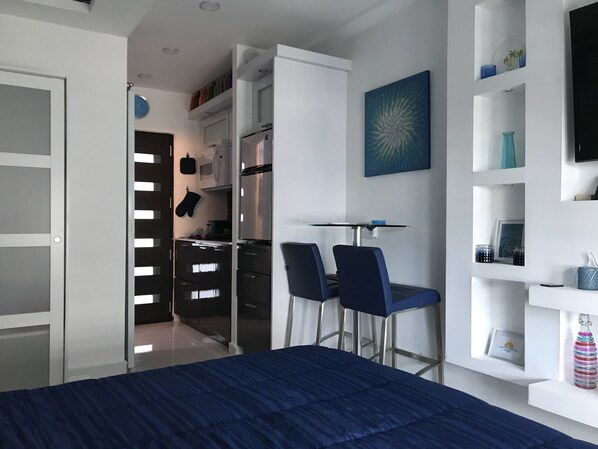 Ein modernes Schlafzimmer mit einem Bett, einem Schreibtisch mit Stühlen, einem Kleiderschrank und einem Regal mit Dekoration.