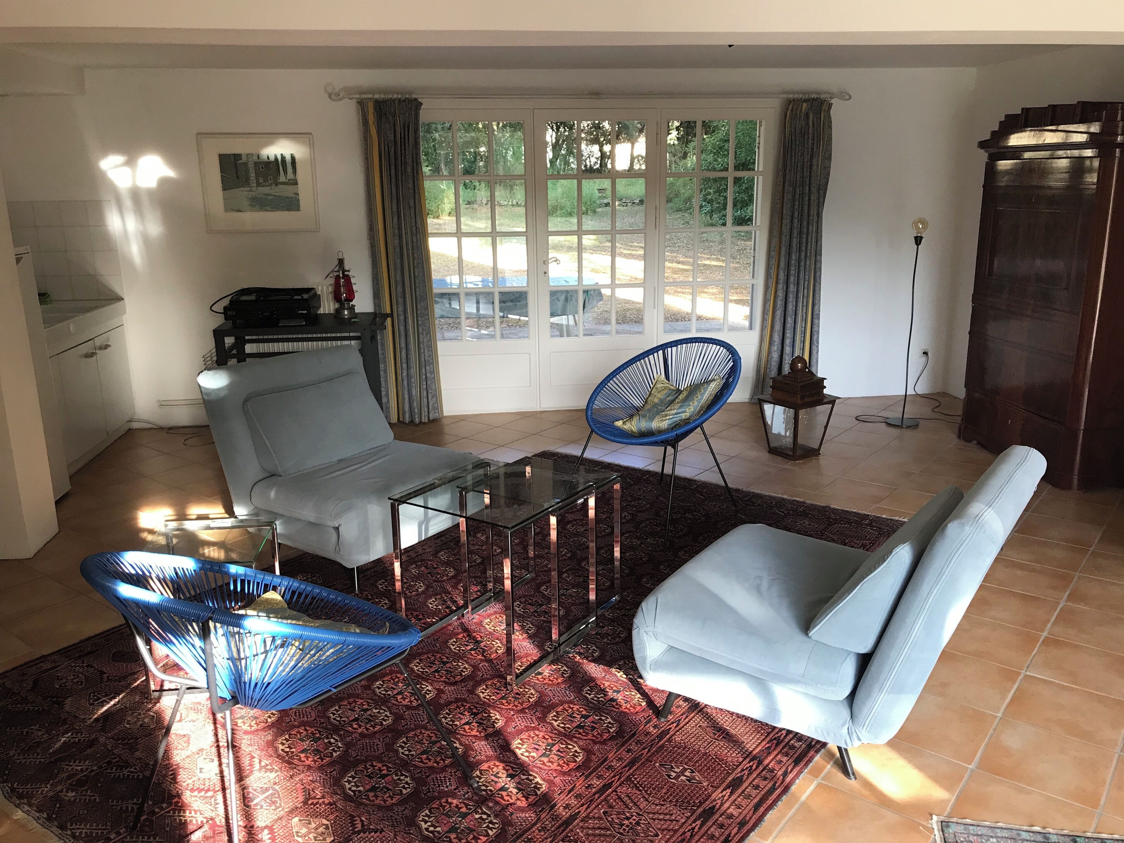A living room with a sofa, two armchairs, a glass coffee table, and a patterned rug.