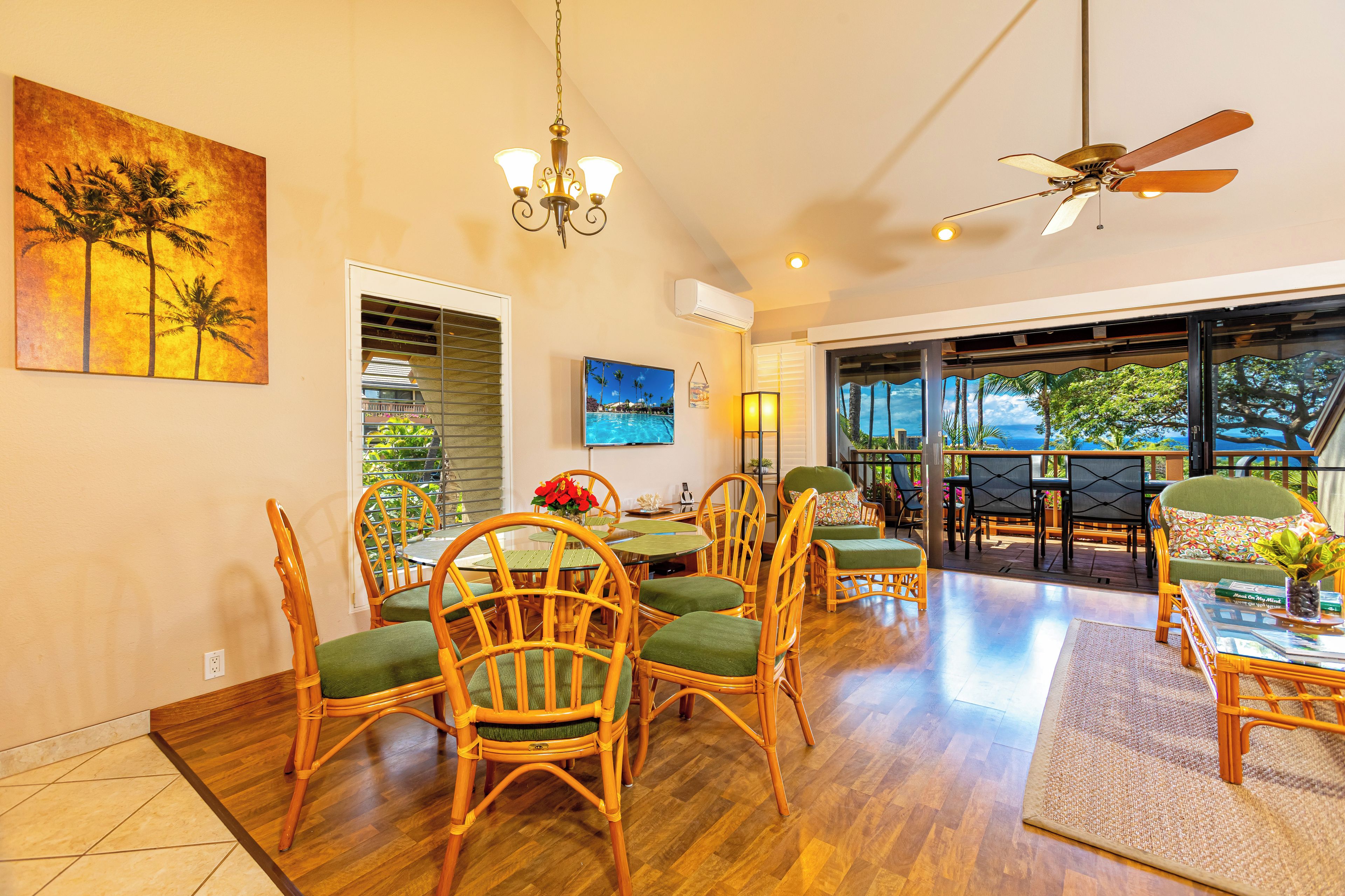 A spacious dining area with wooden chairs and a table, a chandelier, and a view through large windows.