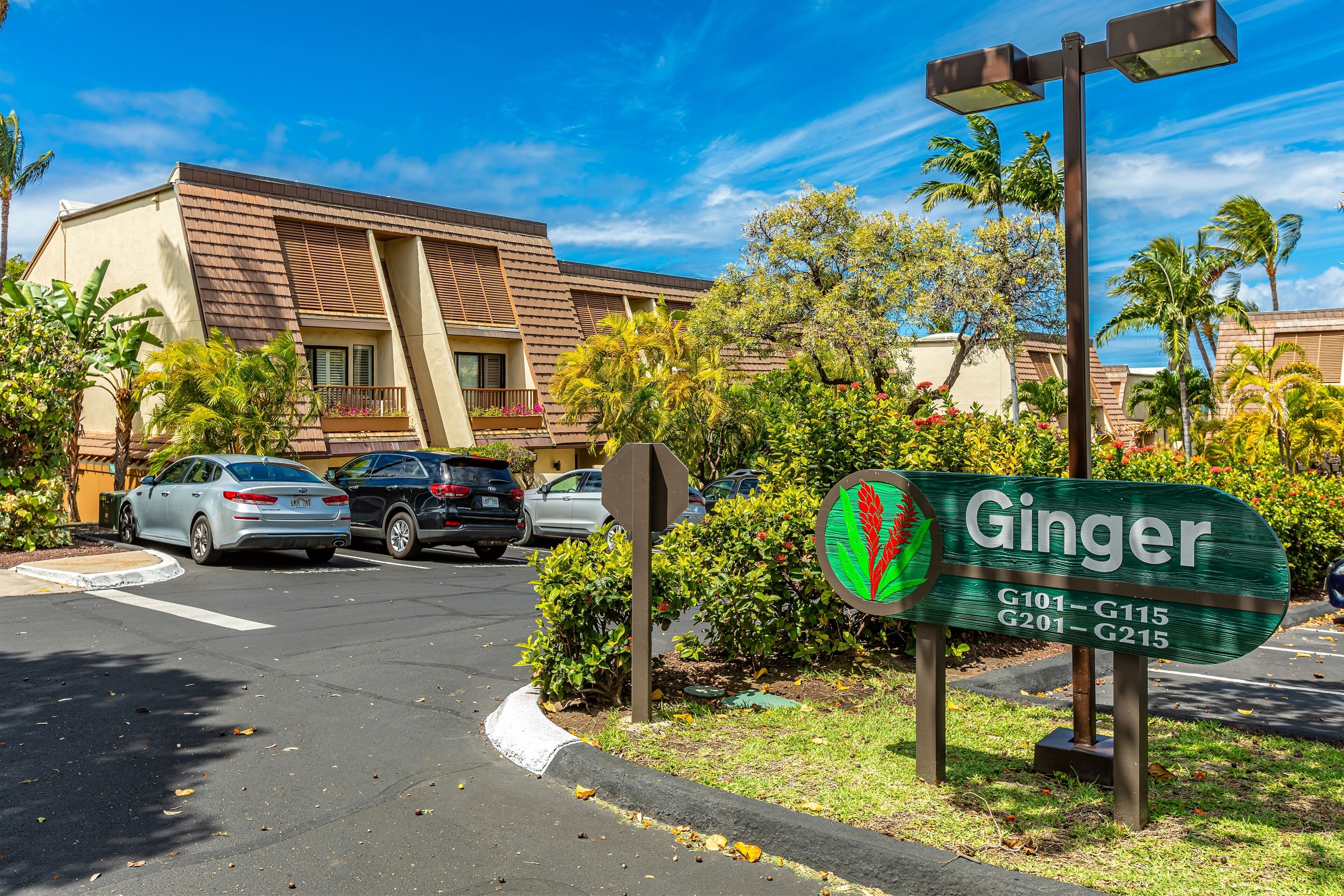 Een hotelschbord met de naam 'Ginger' en een parkeerplaats met auto's.