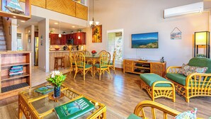 A spacious living area with a dining table, wicker furniture, and a view of the kitchen. - Maui Kamaole #G-201 Front Row, Ocean View, Full A/C, Hot Tub, Great Rates (Kihei)