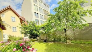 Un quartier résidentiel avec une pelouse bien entretenue, des plantes fleuries et un arbre.