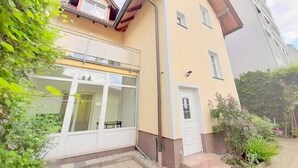 Un immeuble de deux étages avec une façade jaune, un balcon et une porte dotée d’une petite fenêtre.