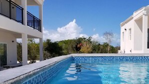 A swimming pool with clear blue water, surrounded by white buildings and greenery. - Tranquil Villa near Long Bay Beach, Pool & Sunsets (Long Bay Hills)