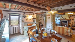 A rustic kitchen with stone walls, wooden beams, and a dining area with a table set for two. - 4 bedroom cozy home in Camaiore (Camaiore)