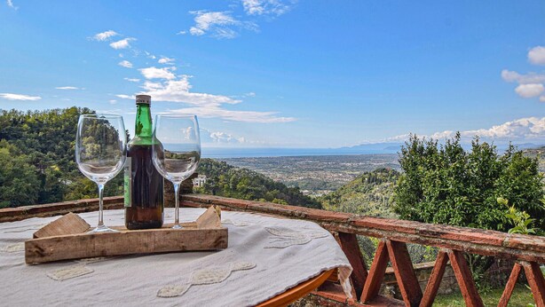 A table with a bottle and two glasses on a terrace overlooking a cityscape. - 4 bedroom cozy home in Camaiore (Camaiore)