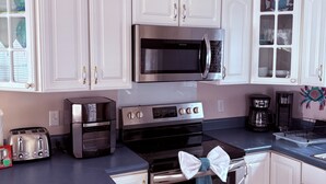 Une cuisine moderne avec des meubles blancs, des appareils en acier inoxydable et un plan de travail bleu.