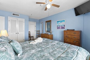A bedroom with a bed, a dresser, a mirror, a ceiling fan, and a TV mounted on the wall. - T2012 at The Myrtle Beach Resort (Myrtle Beach)