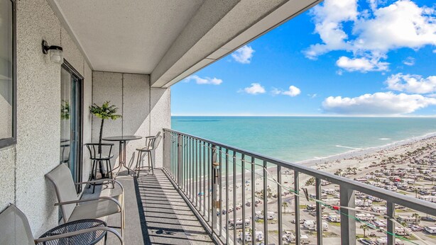 A balcony with a view of the beach, chairs, and a small table. - T2012 at The Myrtle Beach Resort (Myrtle Beach)