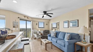 A living room with a blue sofa, a wooden coffee table, a rocking chair, and a ceiling fan. - T2012 at The Myrtle Beach Resort (Myrtle Beach)