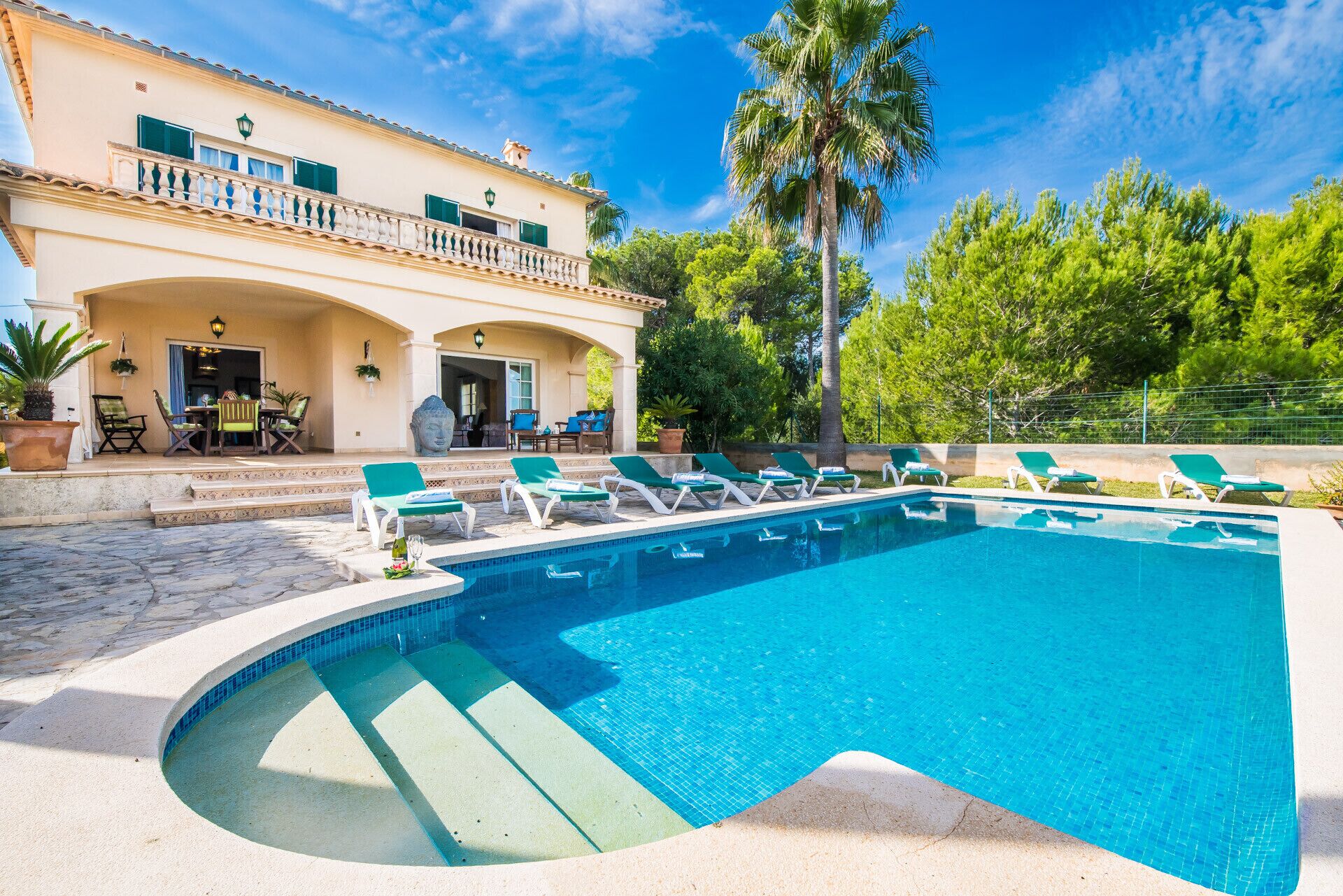 Une piscine avec des chaises longues, un patio couvert et un bâtiment doté d’un balcon.