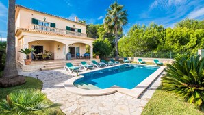 Ein zweistöckiges Gebäude mit Pool, Sitzgelegenheiten im Freien und einer überdachten Terrasse.