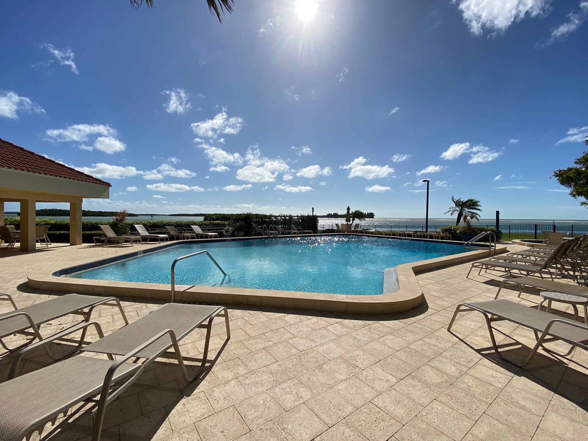 A pool area with lounge chairs and a view of the sea.