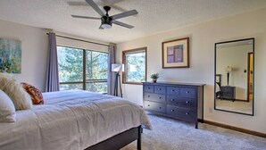 A bedroom with a bed, dresser, and large windows. - The Evergreen Gem| Mountain Experience Retreat (Evergreen)