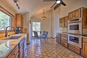 Una cocina con suelo de baldosas hexagonales, armarios de madera, electrodomésticos de acero inoxidable y una zona de comedor con sillas.