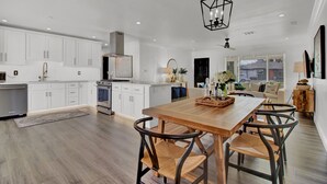 A spacious kitchen with white cabinetry, a wooden dining table, and a central island. - Level up your Old Town stay- Walk to bars- 2 Kings (Scottsdale)
