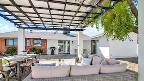 A covered patio area with a wicker sofa, dining table, and chairs. - Level up your Old Town stay- Walk to bars- 2 Kings (Scottsdale)