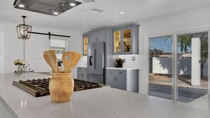 A modern kitchen with a large island, grey cabinets, and a stainless steel refrigerator. - Level up your Old Town stay- Walk to bars- 2 Kings (Scottsdale)