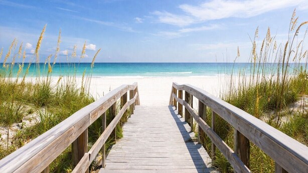 A wooden boardwalk leading to a beach with clear turquoise water and a clear sky. - Vacation home just steps away from the Gulf (Pensacola Beach)