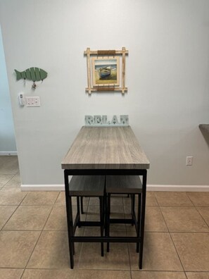A dining table with two chairs, a wall-mounted picture frame, and a wall outlet. - Right ON world’s whitest beach, Pensacola Beach, Florida. (Pensacola Beach)