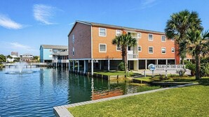 A waterfront building with a sign reading 'Villas on the Gulf' and a water feature in front. - Vacation home just steps away from the Gulf (Pensacola Beach)