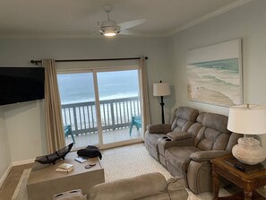 A living room with a sofa, a television, a lamp, and a view of the ocean through a sliding door. - Right ON world’s whitest beach, Pensacola Beach, Florida. (Pensacola Beach)