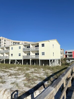 A beachfront building with multiple balconies, a wooden boardwalk, and a clear blue sky. - Right ON world’s whitest beach, Pensacola Beach, Florida. (Pensacola Beach)