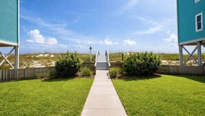 A pathway leading to a beach house with a wooden deck and a view of the beach. - Vacation home just steps away from the Gulf (Pensacola Beach)