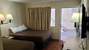 A hotel room with two beds, a desk, a chair, and a window with curtains. - Motel 9 Las Cruces (Las Cruces)